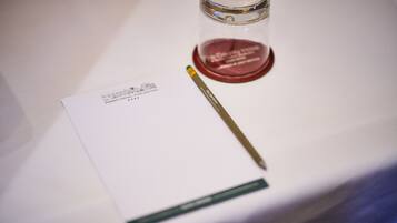 Una mesa blanca con una tarjeta de presentación, un bolígrafo y un pequeño recipiente.