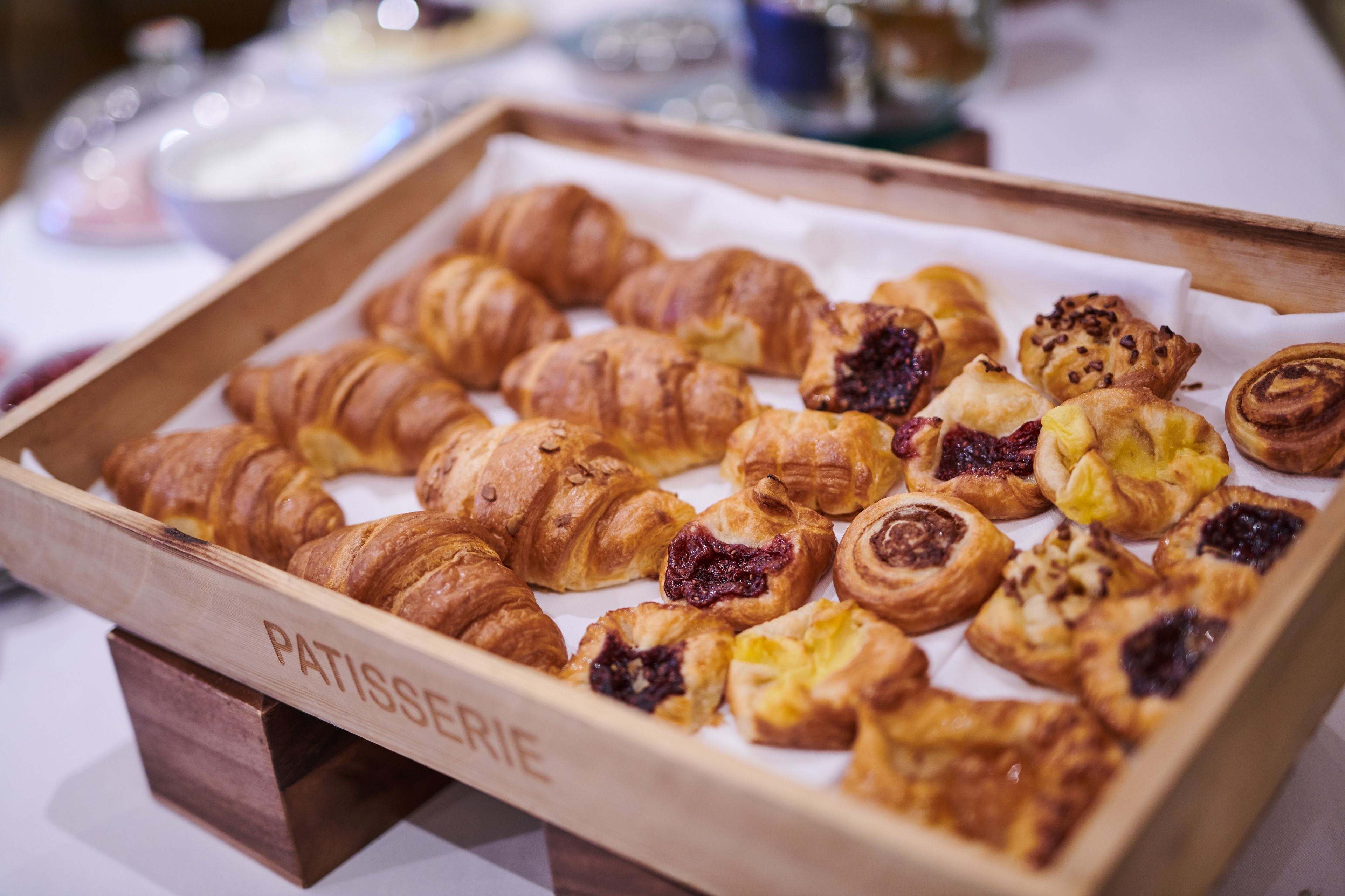 Una bandeja de madera con una variedad de pasteles, incluyendo croissants y tartaletas de fruta.