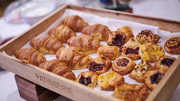 Una bandeja de madera con una variedad de pasteles, incluyendo croissants y tartaletas de fruta.