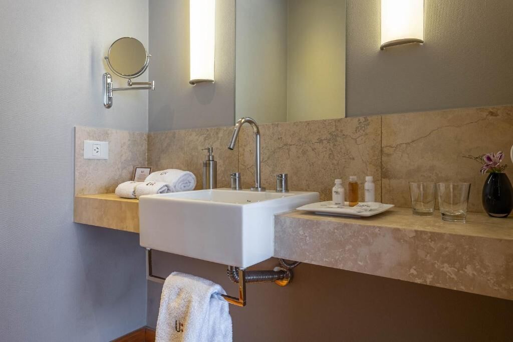 A bathroom with a white sink, a mirror, and a towel rack.