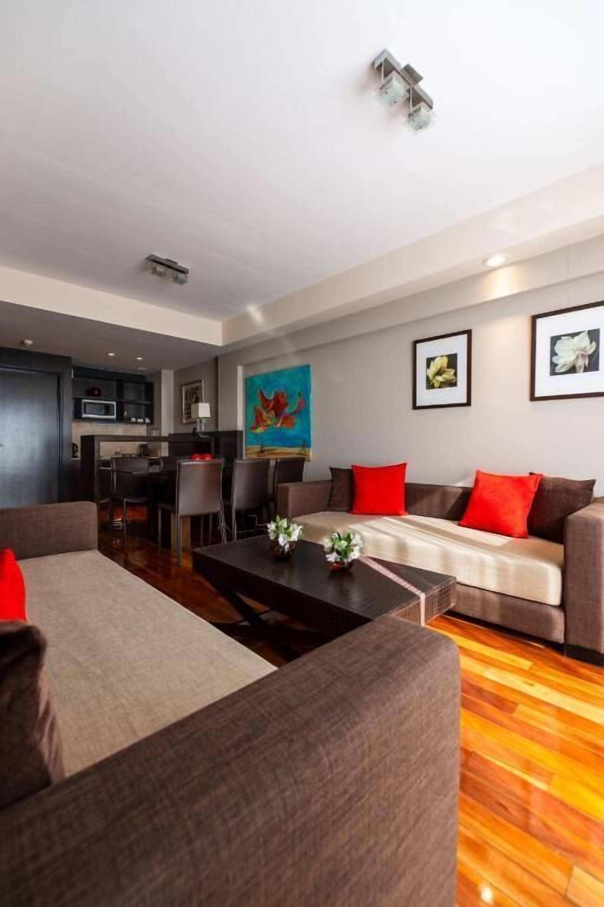 A modern living room with a sofa, coffee table, and a dining area with chairs.