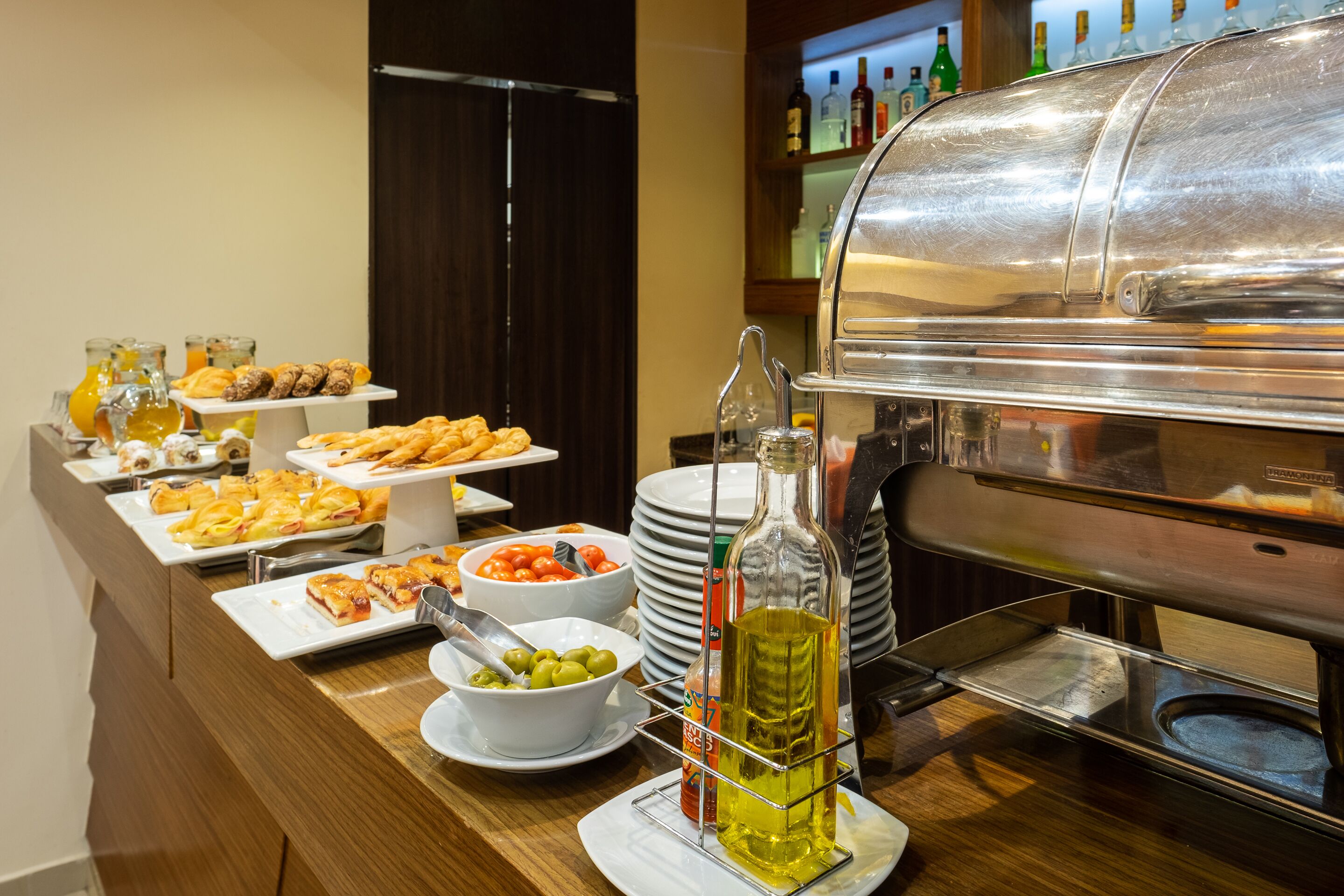 Una mesa de buffet con diferentes opciones de comida, como pasteles, ensaladas y una botella de aceite de oliva.