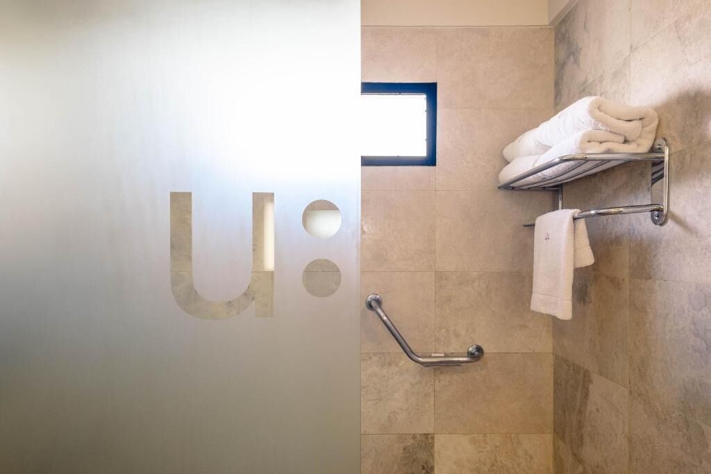 Un baño con baranda, perchero con toallas y una ventana empotrada.