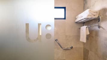 Un baño con baranda, perchero con toallas y una ventana empotrada.