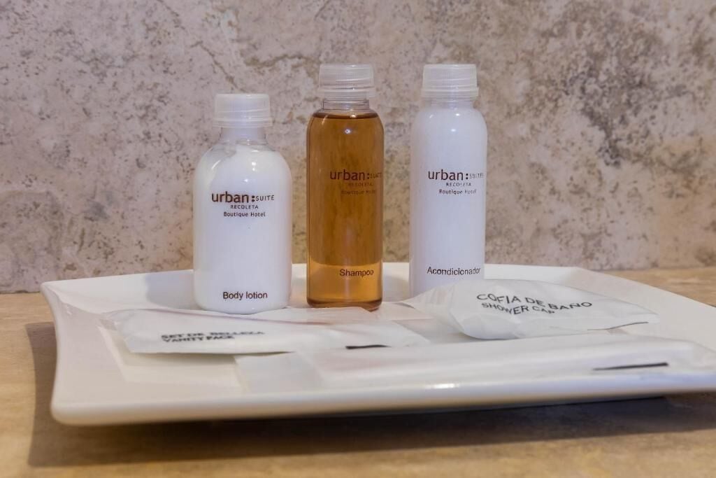 Una bandeja con tres botellas de loción corporal, champú y gel de ducha Urban Suite, junto con un pequeño paquete.