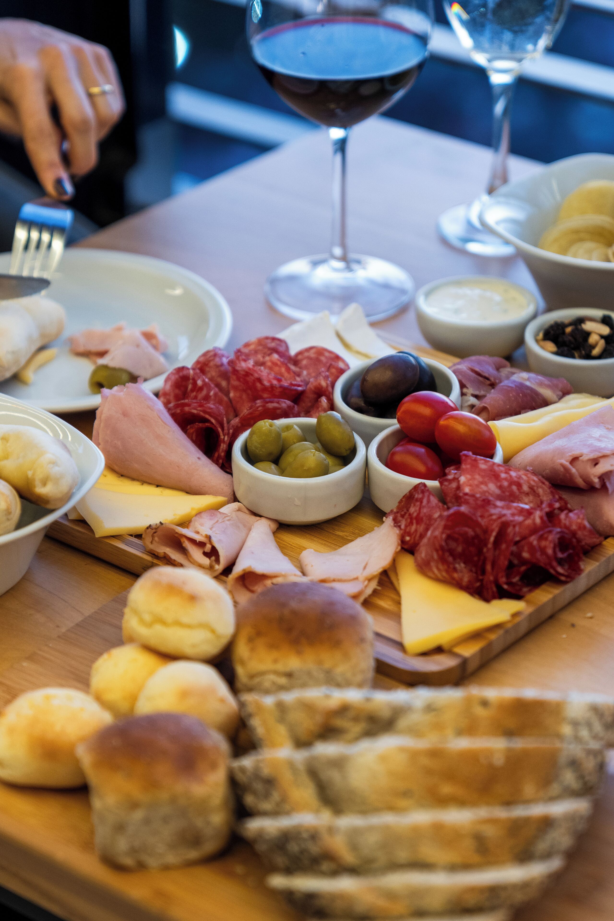 A charcuterie board with various meats, cheeses, olives, and bread.