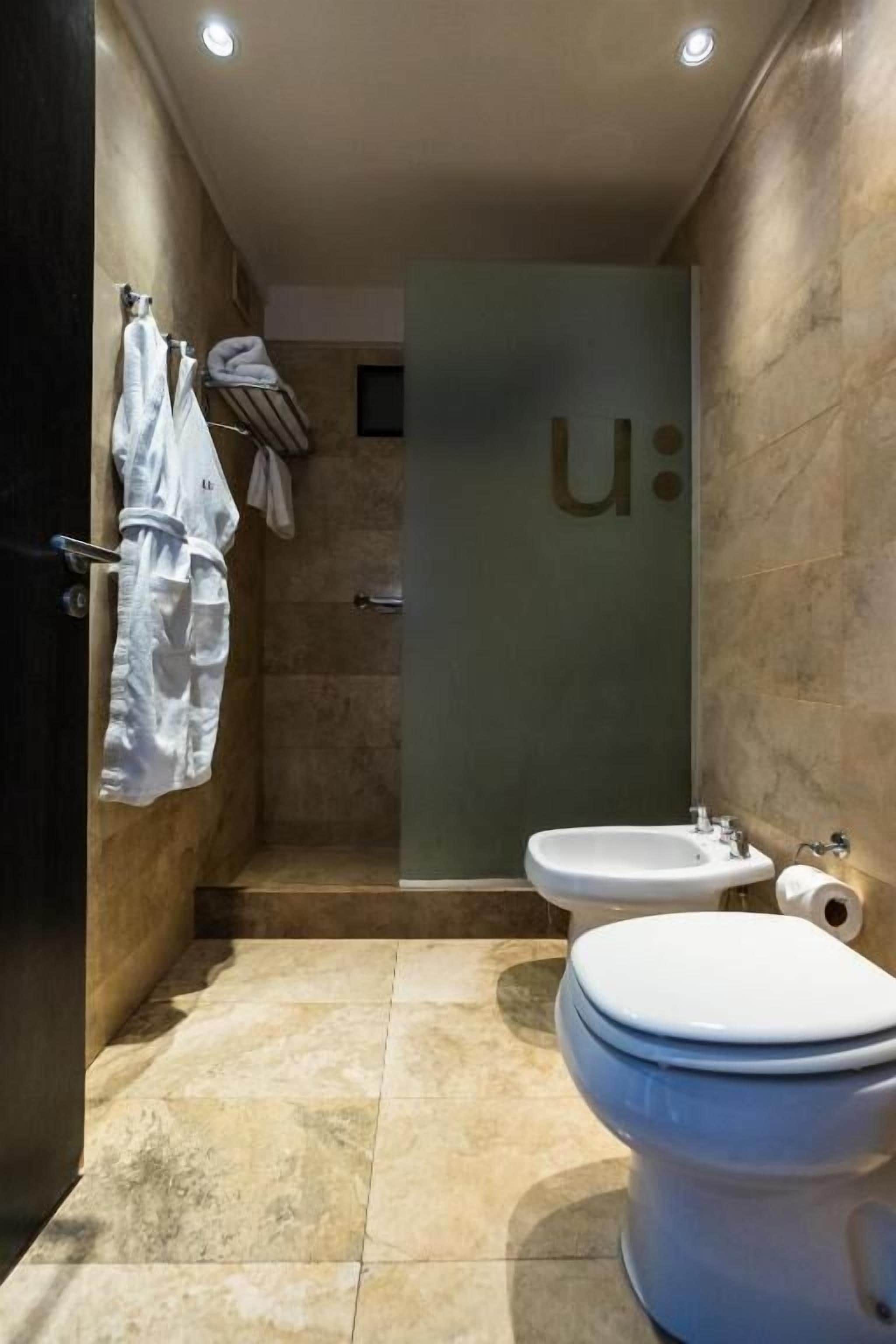 A modern bathroom with a toilet, bidet, and towel rack.