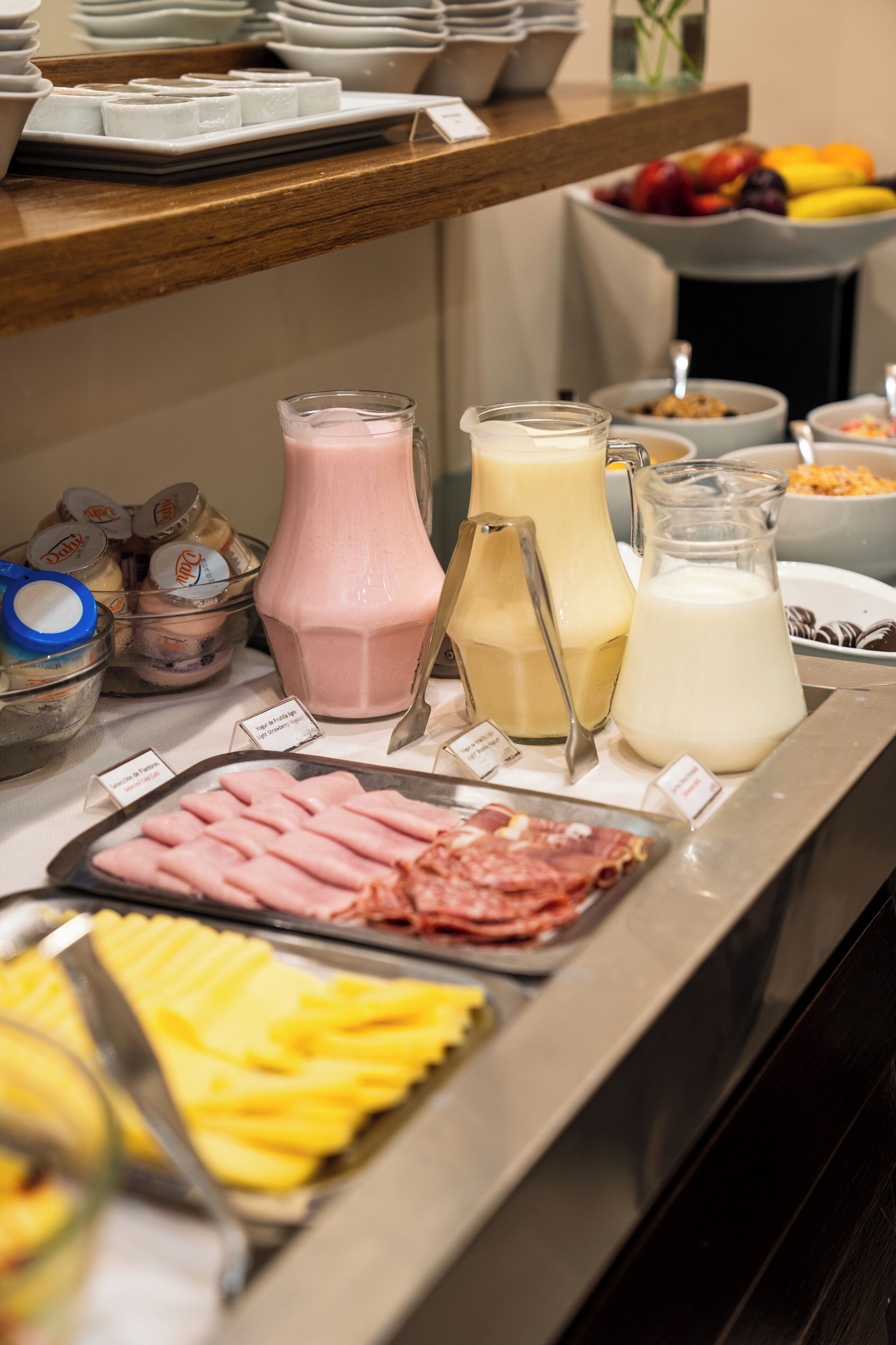 A buffet with various food items including meats, fruits, and beverages.
