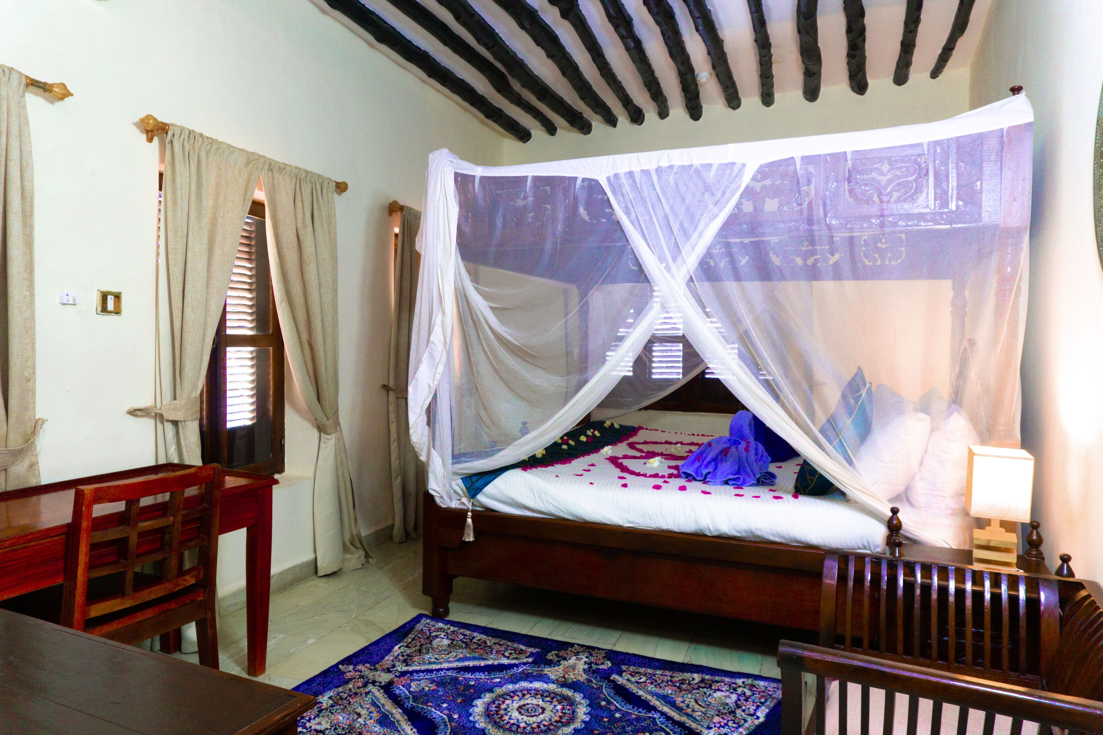A bedroom with a wooden bed, a nightstand, a desk, and a chair.
