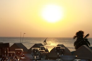 A table set for dinner with glasses and a bowl, overlooking the ocean at sunset. - Al Johari Hotel & Spa (Zanzibar Town)