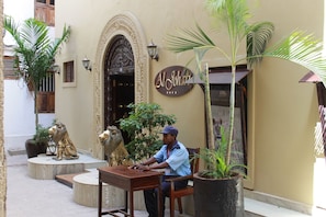 Un homme est assis à une table devant un bâtiment sur lequel on peut lire l’inscription « Al Johah ».