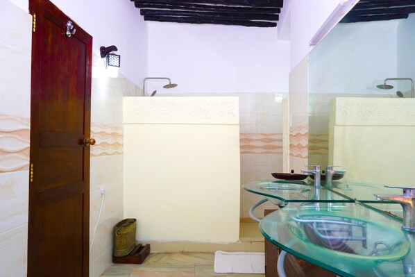 A bathroom with a glass sink, a wooden door, and a towel on the floor.