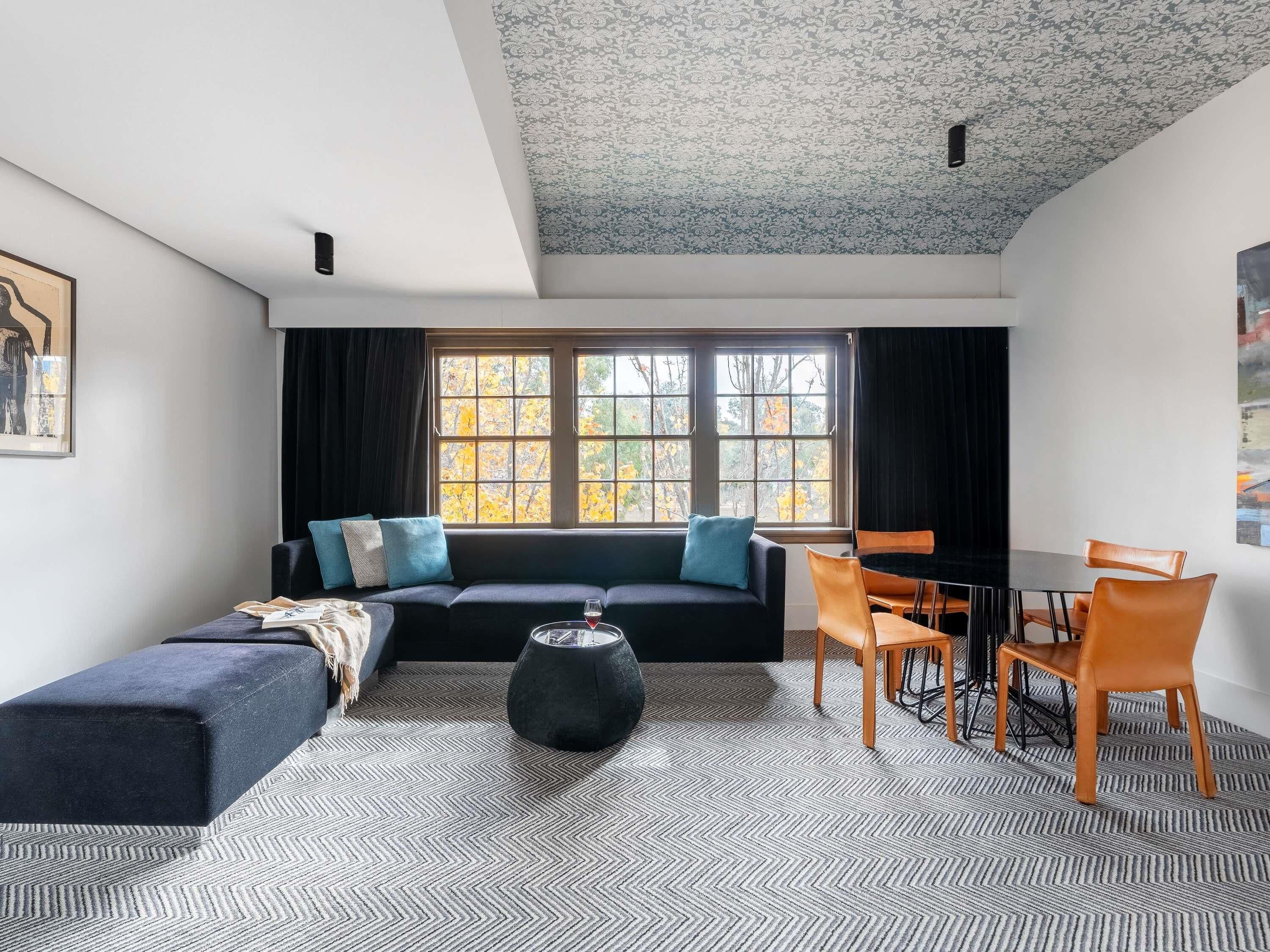 A modern living room with a sofa, ottoman, coffee table, and dining area with chairs.
