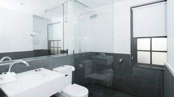 Un baño moderno con ducha envuelta en vidrio, un lavabo blanco y un inodoro.