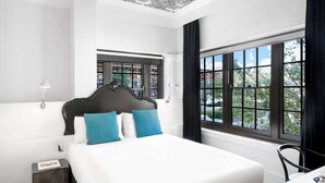 Ein Hotelzimmer mit einem großen Bett, einem Fenster mit Blick, einem Nachttisch und einem Sessel.