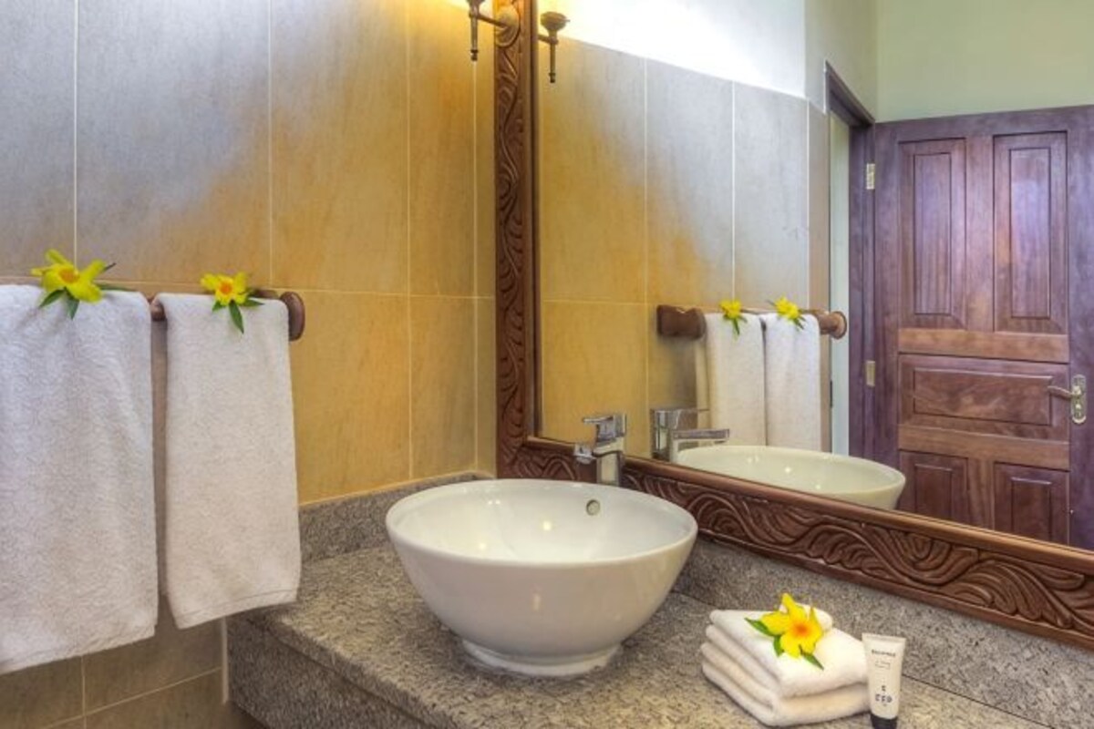 Ein Badezimmer mit einem großzügigen Waschbecken, zwei Handtüchern und einem Spiegel mit Holzrahmen.