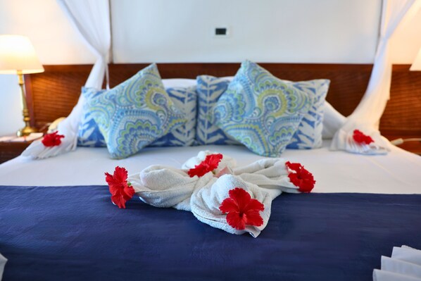 A neatly made bed with patterned pillows, a blue bedspread, and red flowers.