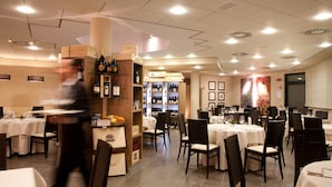 A restaurant with multiple tables, chairs, and a wine display.