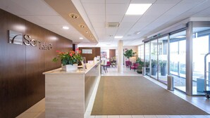 A reception area with a reception desk, a plant, and a seating area with chairs.