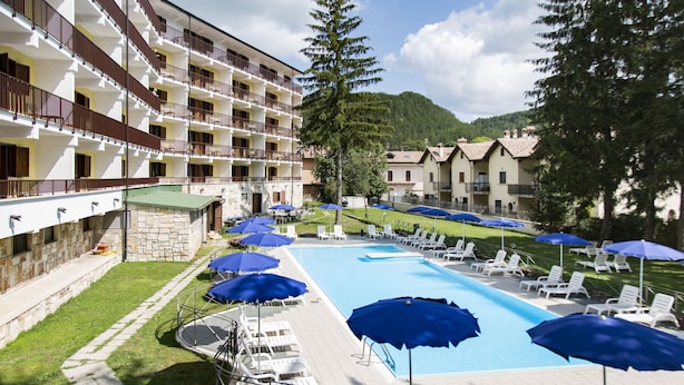 A hotel with a swimming pool, sun loungers, and umbrellas. - Grand Hotel del Parco (Pescasseroli)