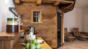 Interior de una cabaña de madera con mostrador de bar, una ventana y una puerta que da a un área exterior con sillas.