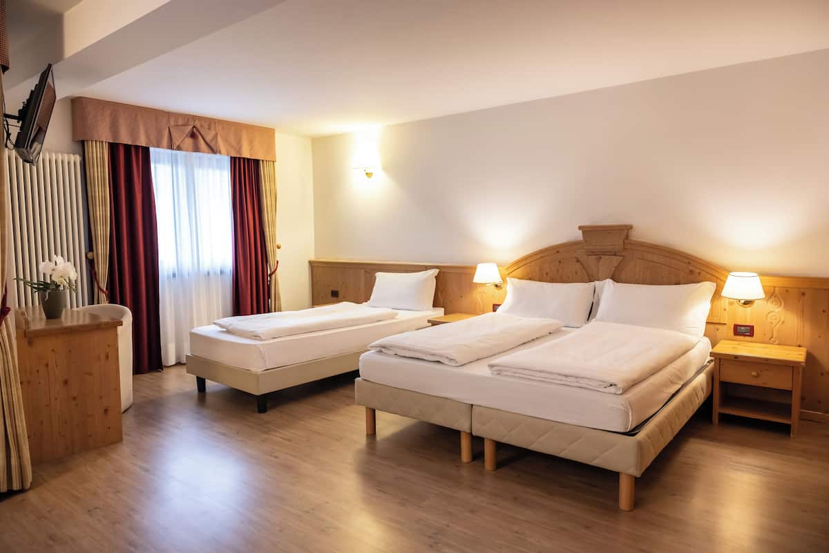 A hotel room with two beds, wooden headboards, bedside lamps, and a wooden dresser.