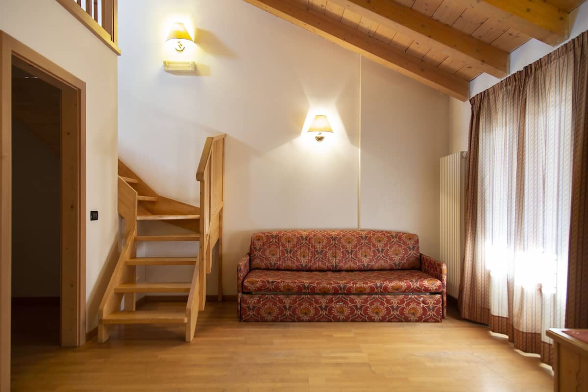 A staircase leading to a loft area, a patterned sofa, and a wall-mounted light fixture.
