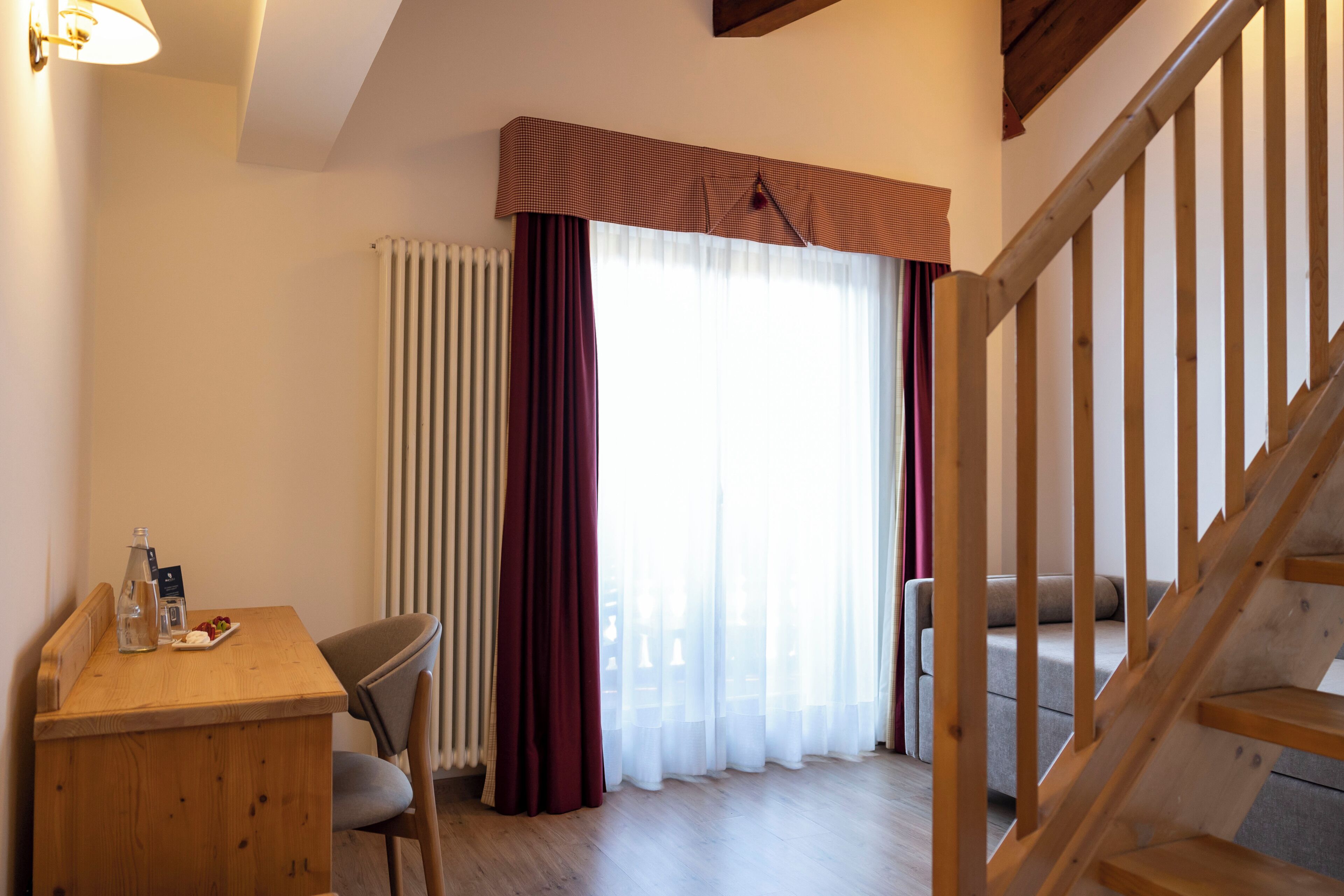 A room with a wooden desk, chair, and a staircase.