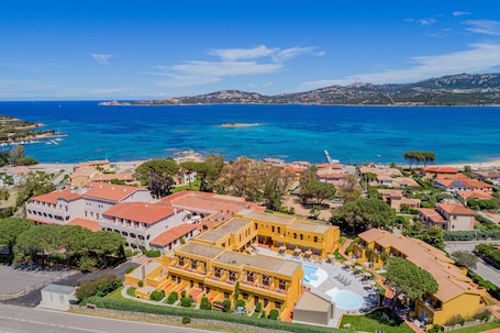 A coastal resort with multiple buildings, a swimming pool, and a view of the sea.