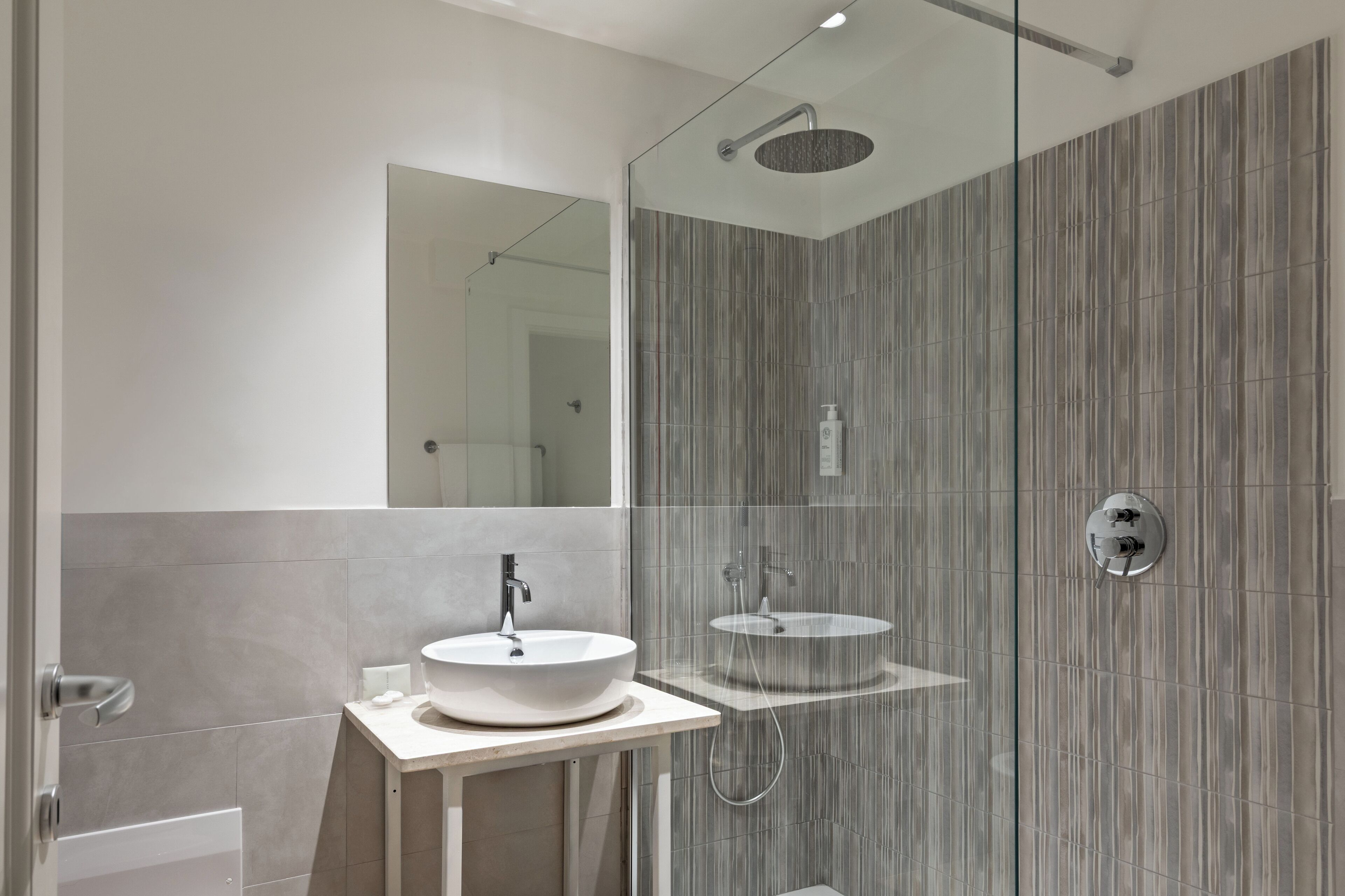 A modern bathroom with a glass-enclosed shower, two sinks, and a large mirror.