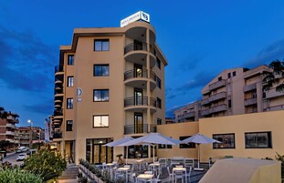 Un hotel con terraza, varios balcones y un cartel que indica que es un hotel.