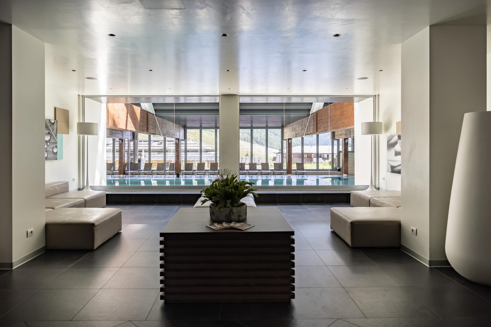 A modern indoor pool area with a view of a mountain landscape.