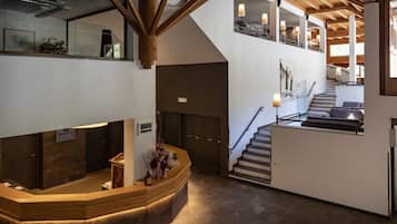 Un vestíbulo de hotel con mostrador de recepción, una escalera y vistas del piso superior.
