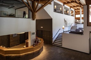 Un hall d’hôtel comprenant un comptoir d’accueil, un escalier et une vue sur l’étage supérieur.