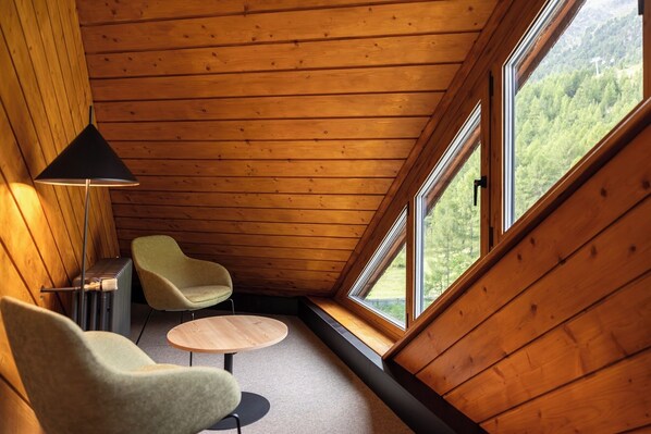 A cozy room with wooden walls, a large window, and two chairs. - Blu Senales Active & Family Resort (Senales)