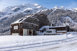 A modern building with a wooden facade and circular windows, set against a snowy mountain backdrop. - Blu Senales Active & Family Resort (Senales)