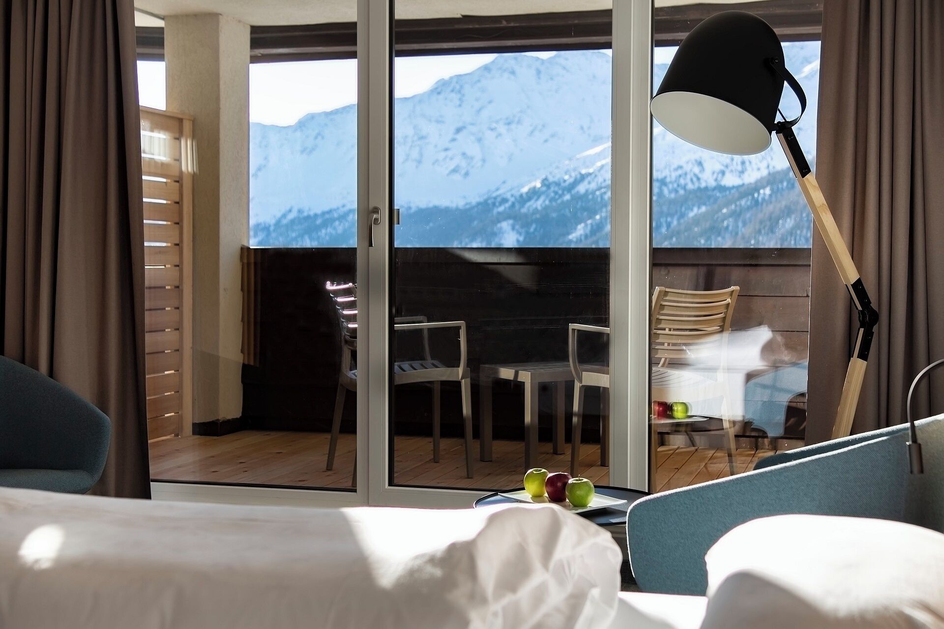 Ein Hotelzimmer mit Balkon, einem Esstisch, Stühlen und Blick auf die Berge.