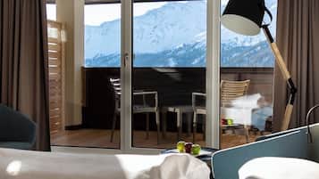 Ein Hotelzimmer mit Balkon, einem Esstisch, Stühlen und Blick auf die Berge.