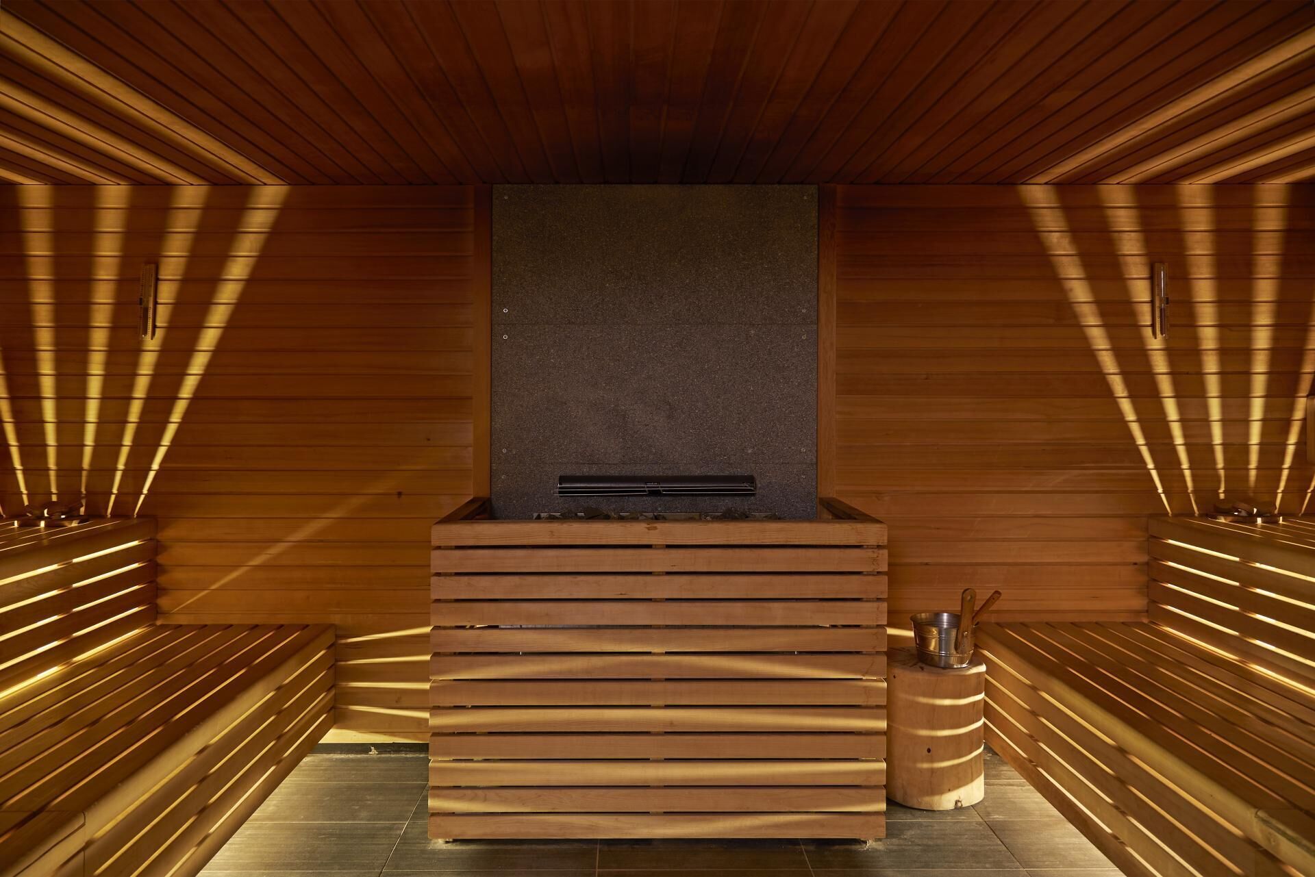 A sauna with a wooden interior, a central bench, and a heater.
