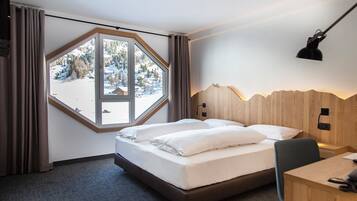 Una habitación de hotel con un ventanal grande, una cama, un escritorio y una lámpara.
