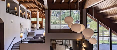 A modern interior with a staircase, seating area, and large windows offering views of the outdoors.