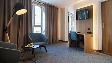 A hotel room with a desk, chair, lamp, and TV.