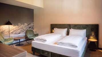 Habitación de hotel con cama, escritorio, silla y lámpara de pared.
