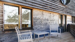A wooden cabin with two white chairs and a small table on the porch. - Blu Senales Active & Family Resort (Senales)