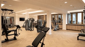 A gym with various exercise equipment, wooden flooring, and large windows. - Blu Senales Active & Family Resort (Senales)