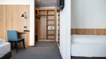Habitació d'hotel amb un llit, un escriptori amb una cadira, un armari i una televisió penjada a la paret.
