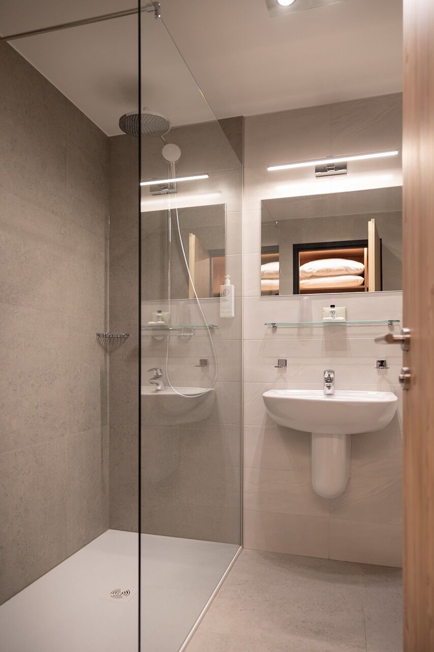 A modern bathroom with a glass shower enclosure, a white sink, and a mirror above the sink.