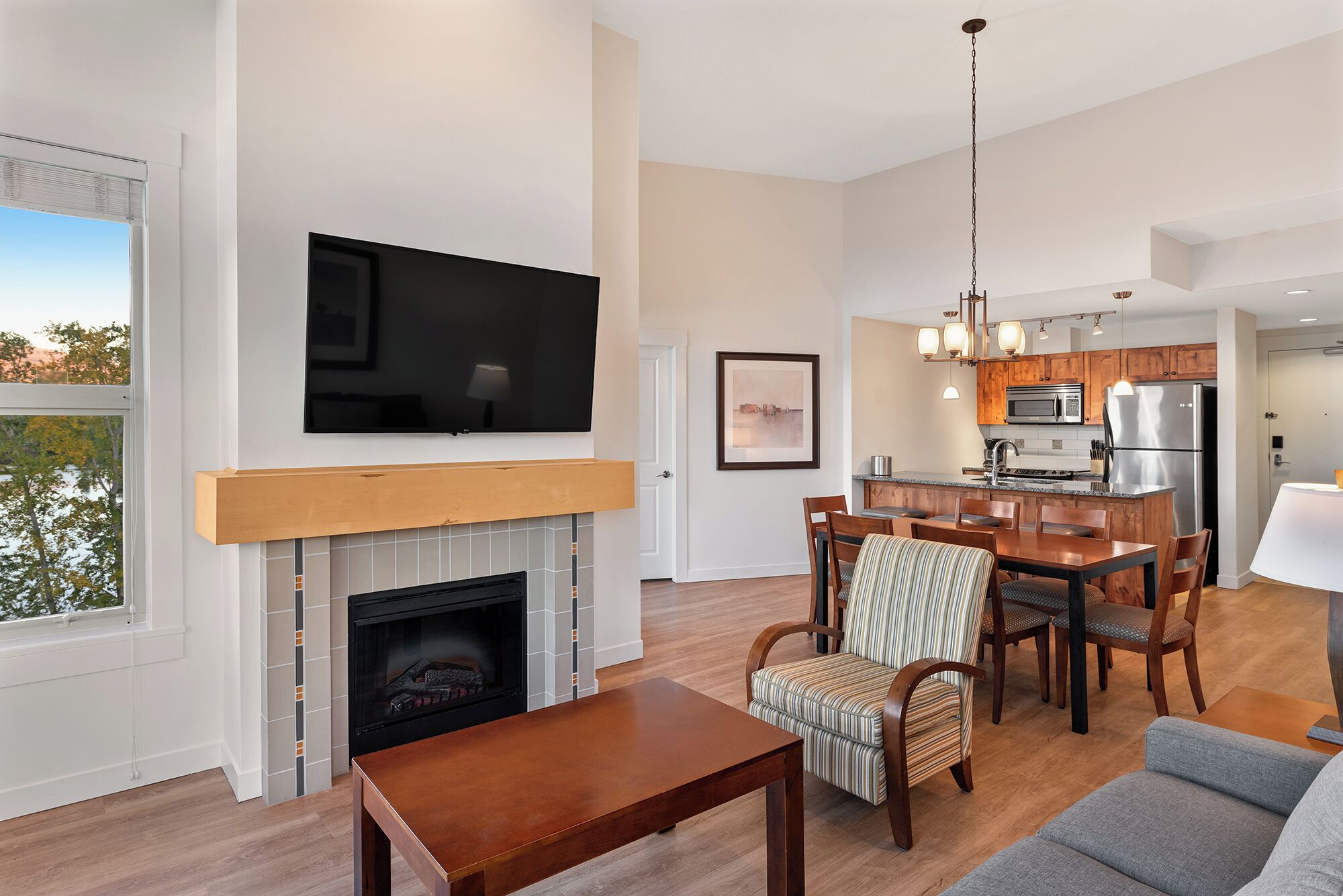 A modern living room with a fireplace, dining area, and kitchen.