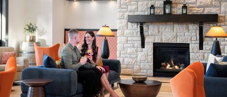 Una sala moderna con chimenea de piedra, muebles naranja y azul, y una mesa de centro.