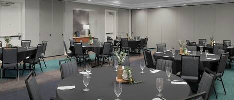 Une salle de conférence dotée de plusieurs tables et chaises, ainsi que de verres et de décorations de table.